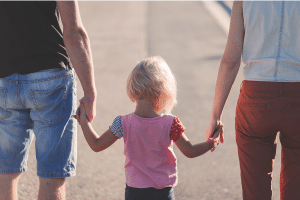 a daughter walking in between her mother and father while holding both of their hands