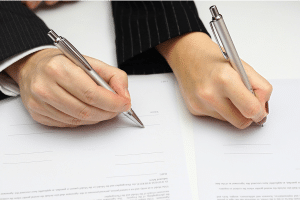 two people signing documents side by side