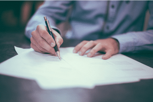 a person writing on paper with a pen