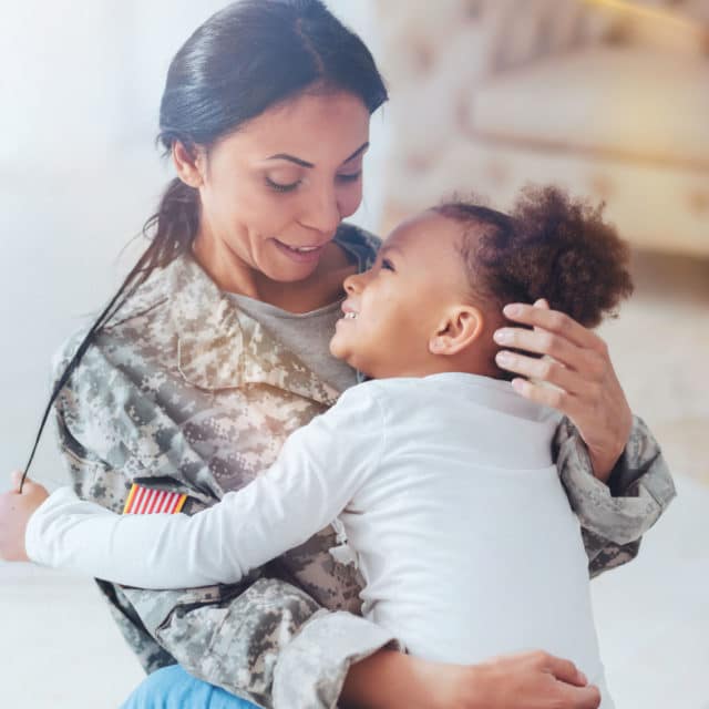 Woman in military uniform hugging a young child