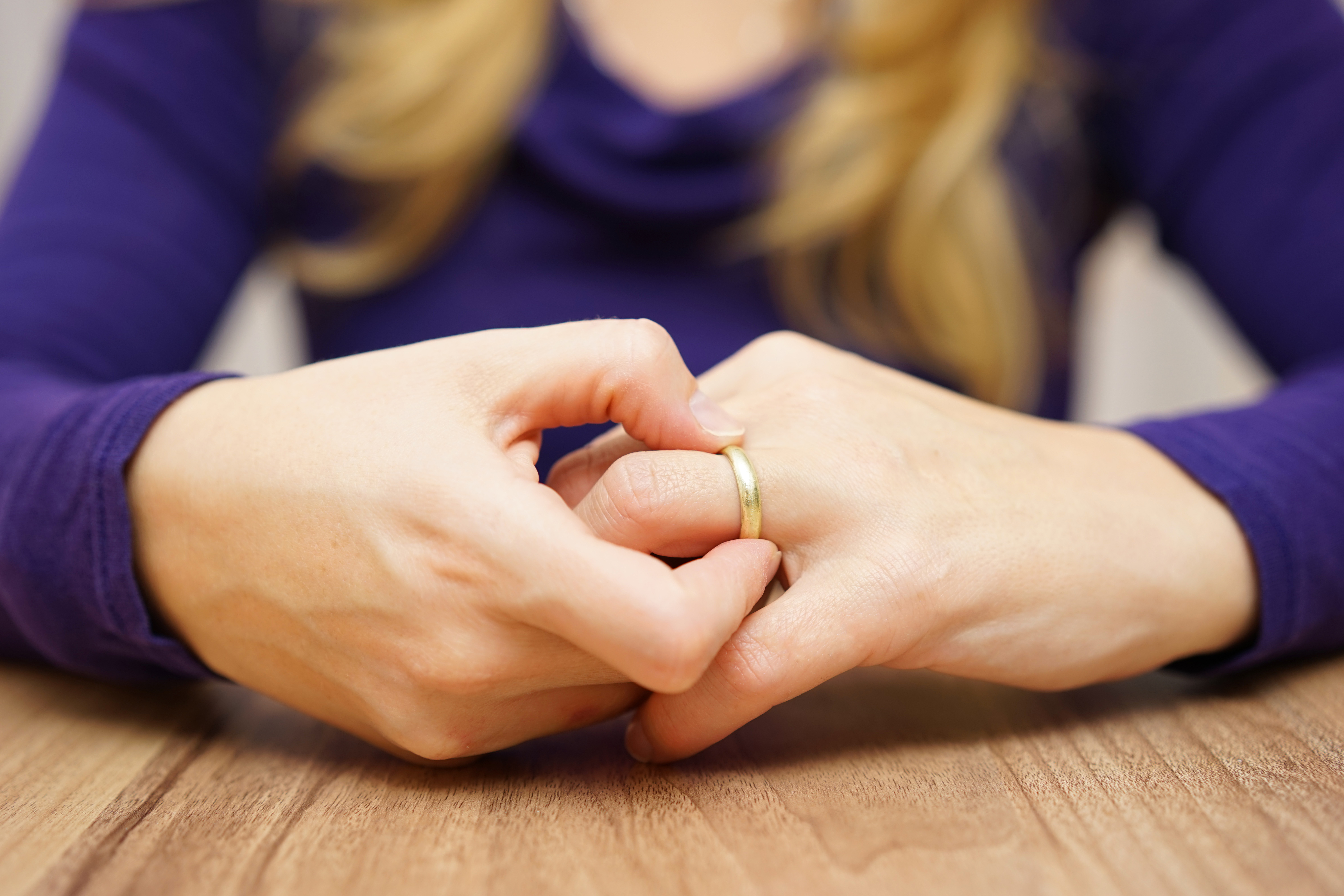woman twisting wedding ring on finger, symbolizing contemplation of divorce