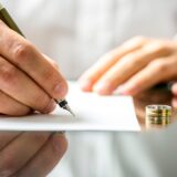 a man signing divorce papers with his wedding ring removed and on the table