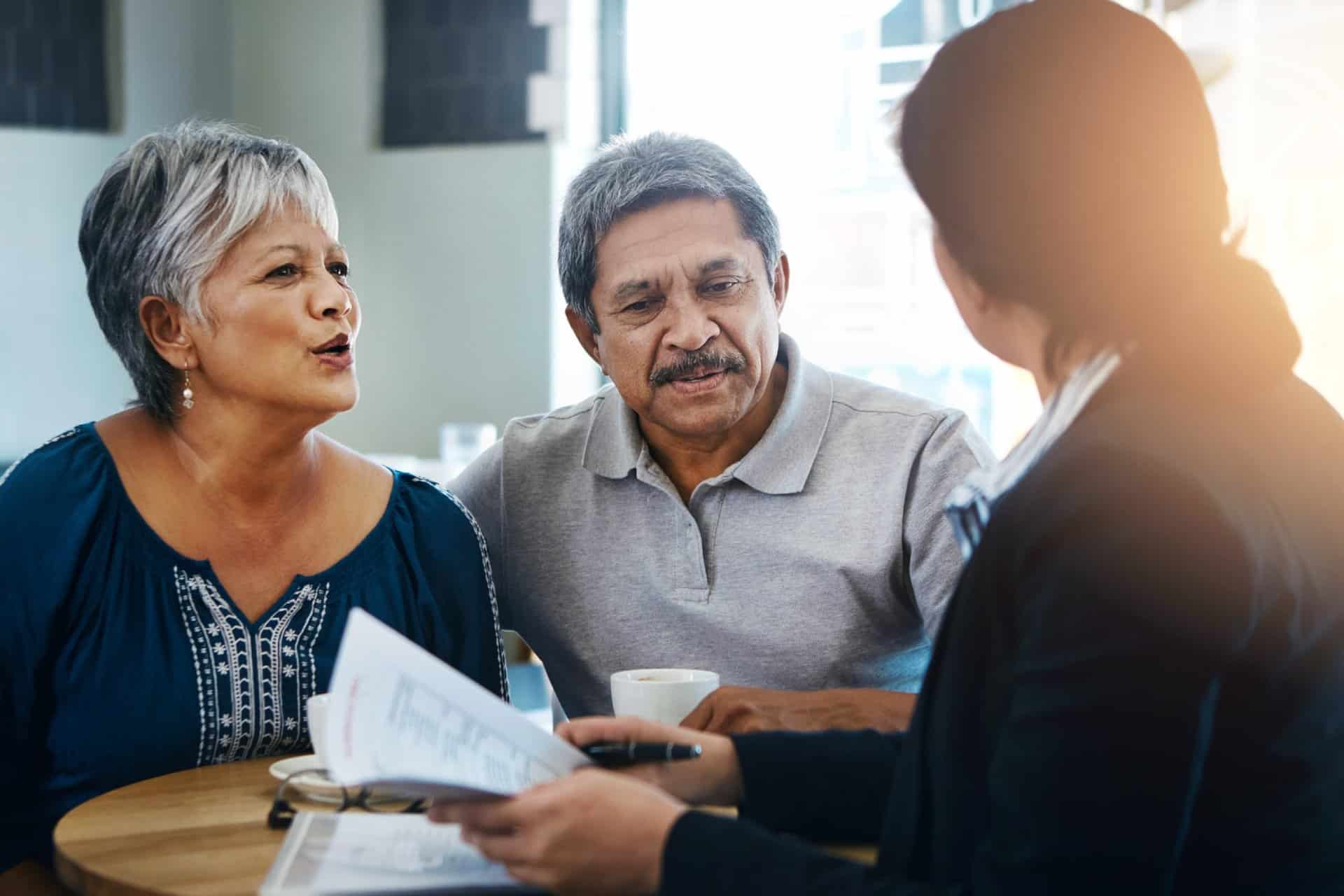 Elderly couple consulting with an advisor, discussing paperwork with attentive expressions